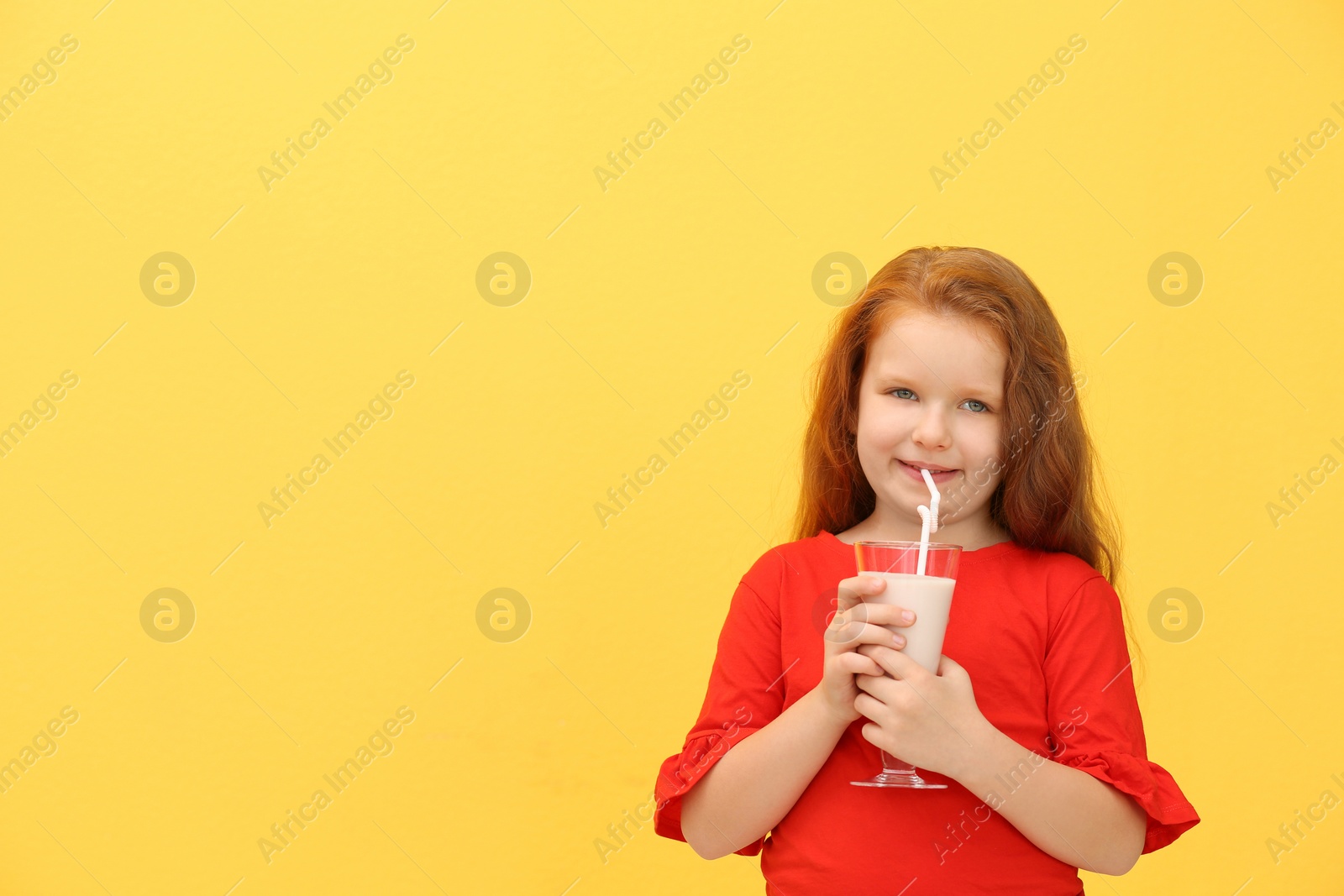 Photo of Little girl with glass of delicious milk shake on color background