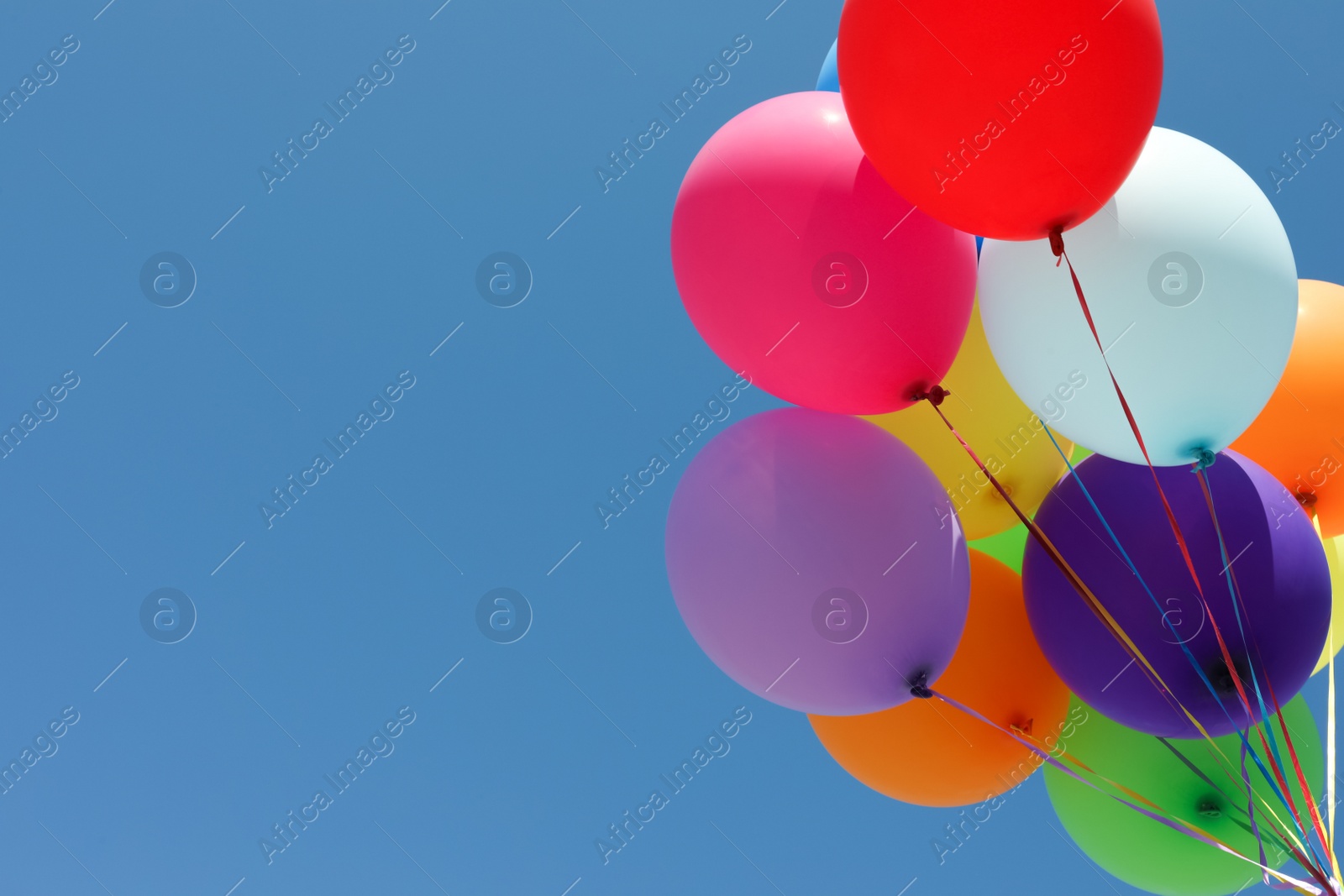 Photo of Bunch of colorful balloons against blue sky, low angle view. Space for text