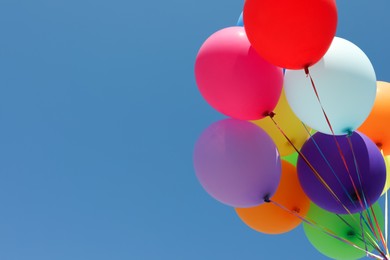 Photo of Bunch of colorful balloons against blue sky, low angle view. Space for text