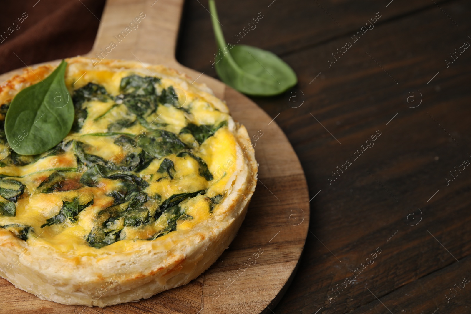 Photo of Delicious pie with spinach on wooden table, closeup