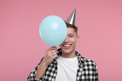 Happy man in party hat with balloon on pink background