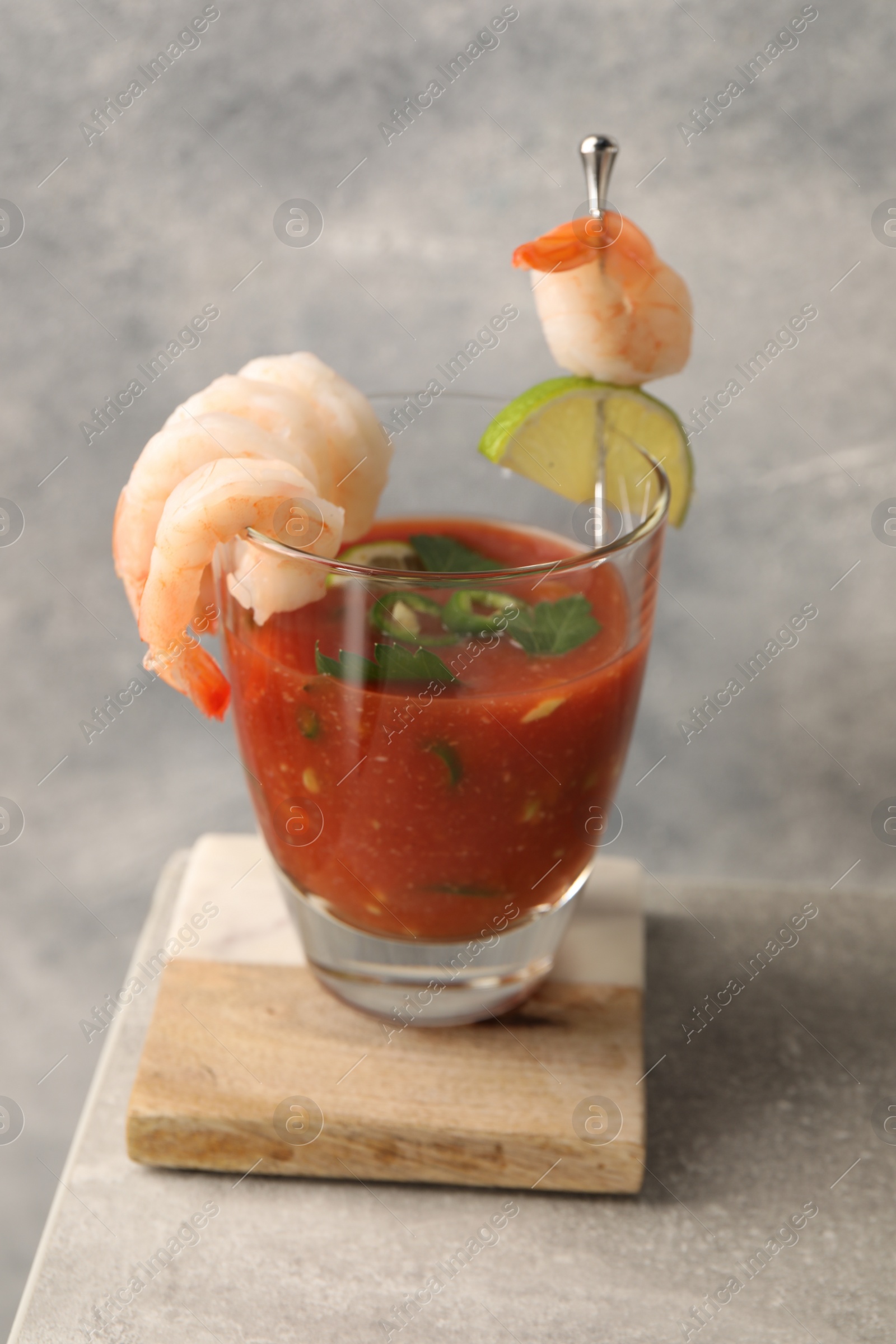 Photo of Tasty shrimp cocktail with sauce in glass and lime on light grey table