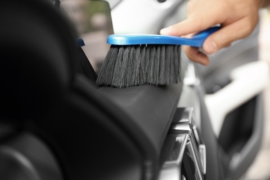 Photo of Man cleaning salon with brush, closeup. Car wash