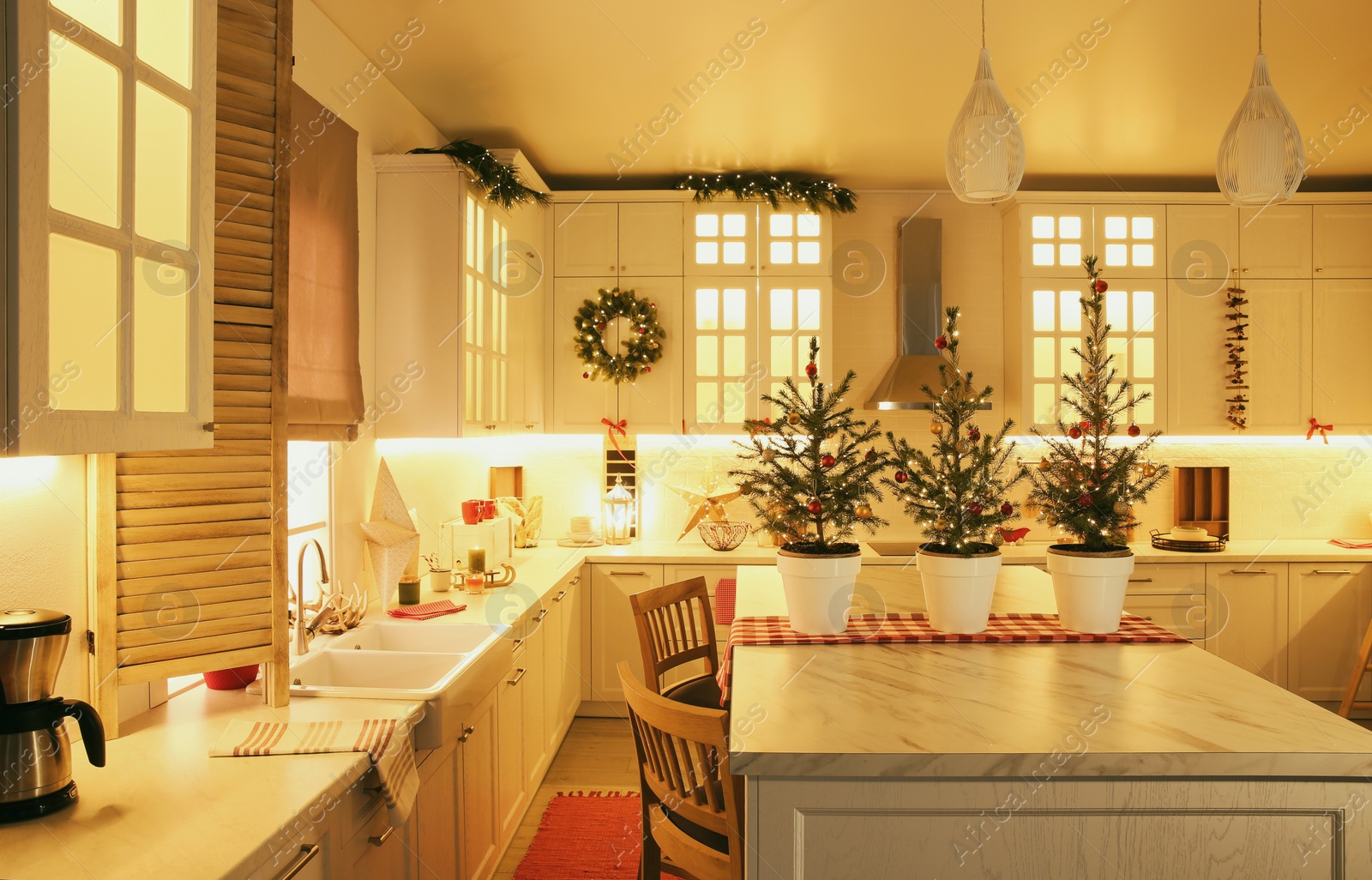 Photo of Small Christmas trees and festive decor in kitchen