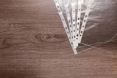 Photo of Punched pockets on wooden table, flat lay. Space for text