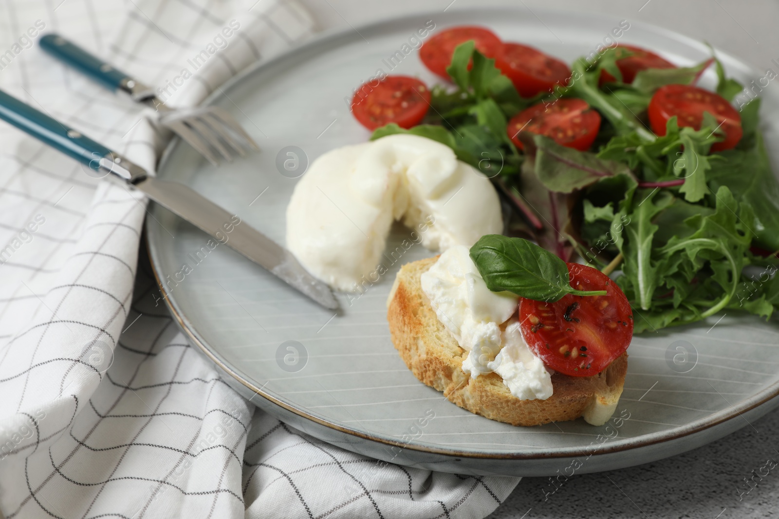Photo of Delicious burrata cheese with tomatoes, arugula and toast served on grey table, closeup