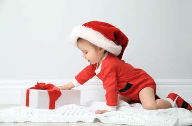 Photo of Cute little baby in Christmas costume with gift at home