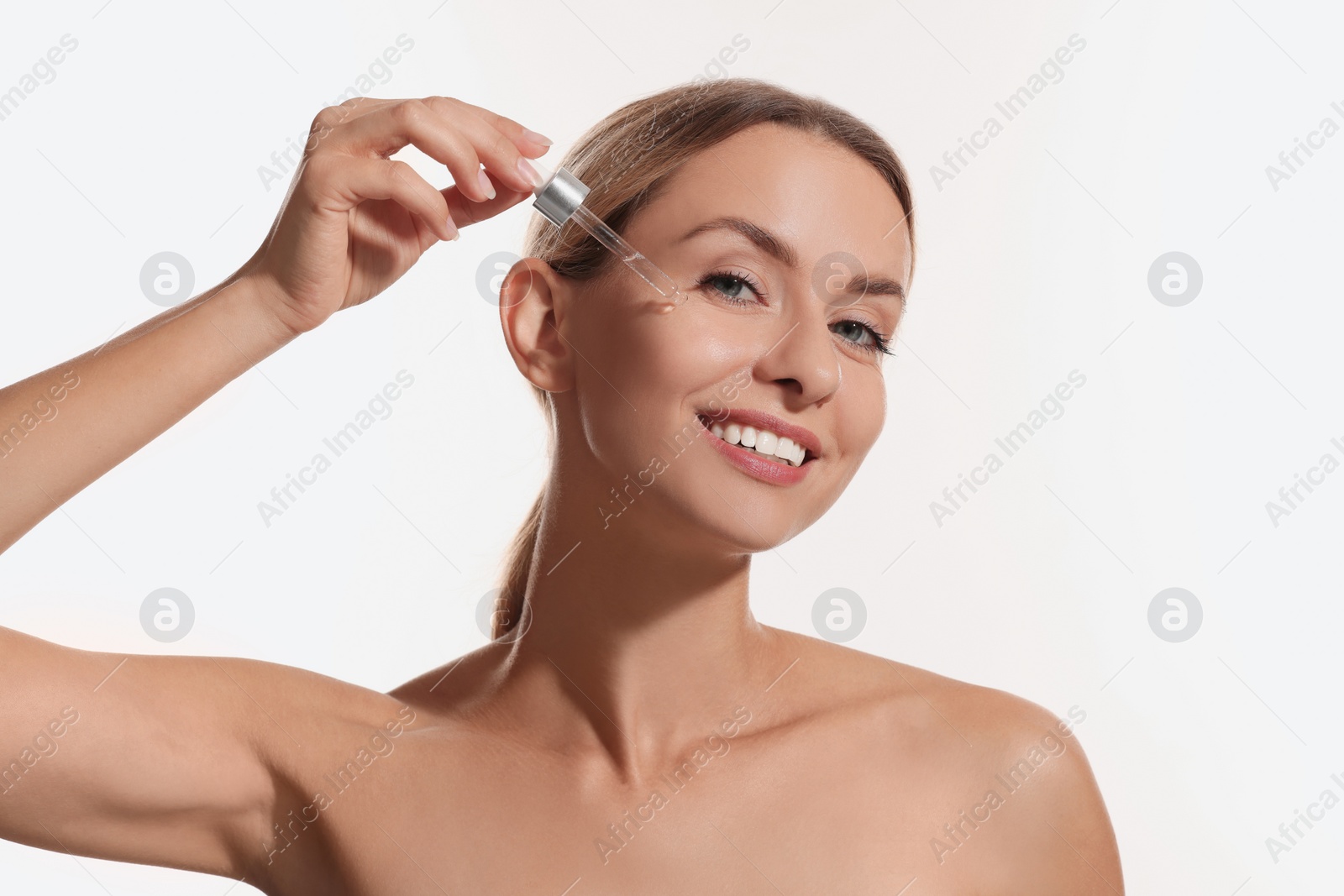 Photo of Beautiful woman applying cosmetic serum onto her face on white background