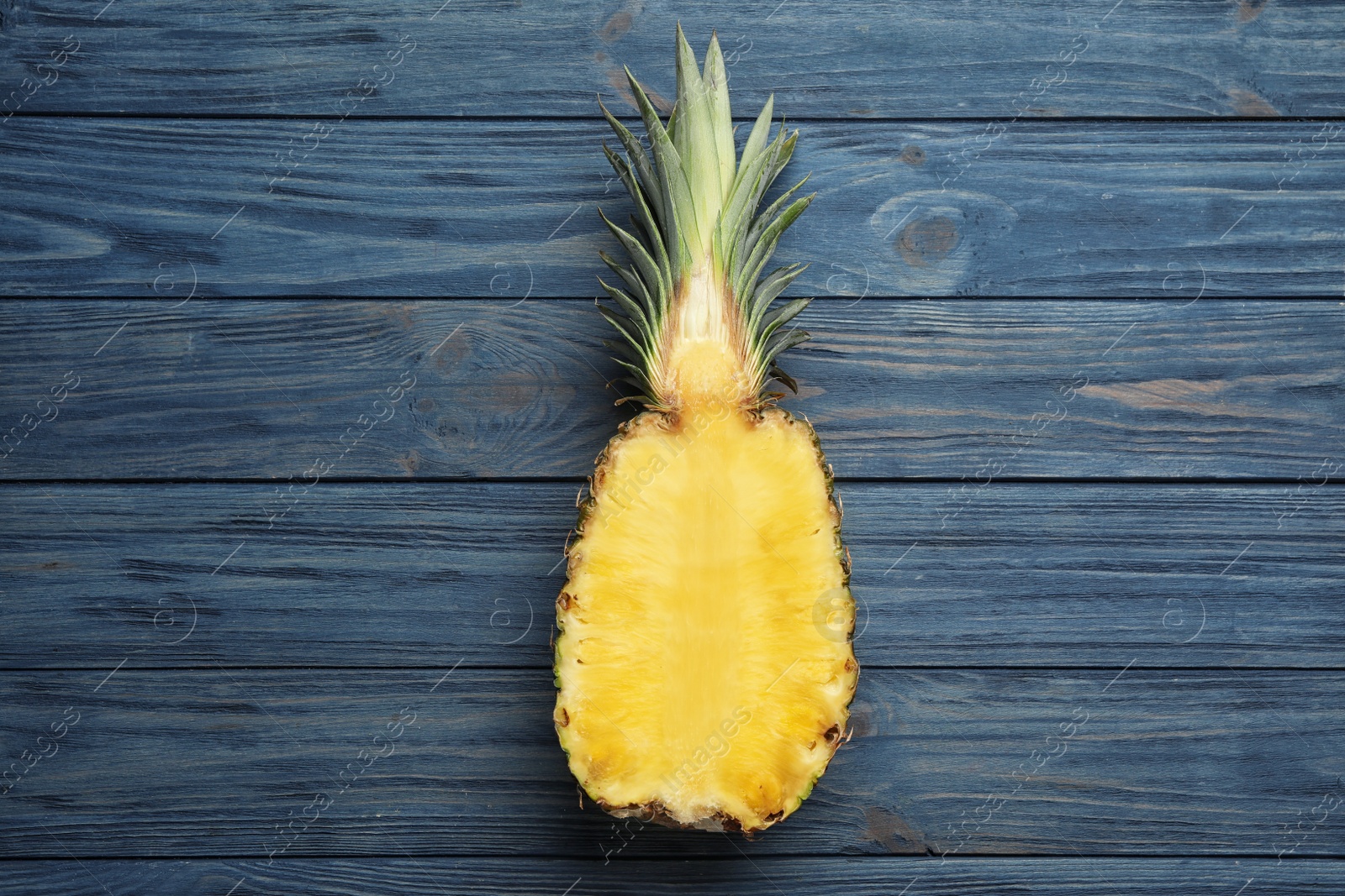 Photo of Half of fresh pineapple on blue wooden background, top view