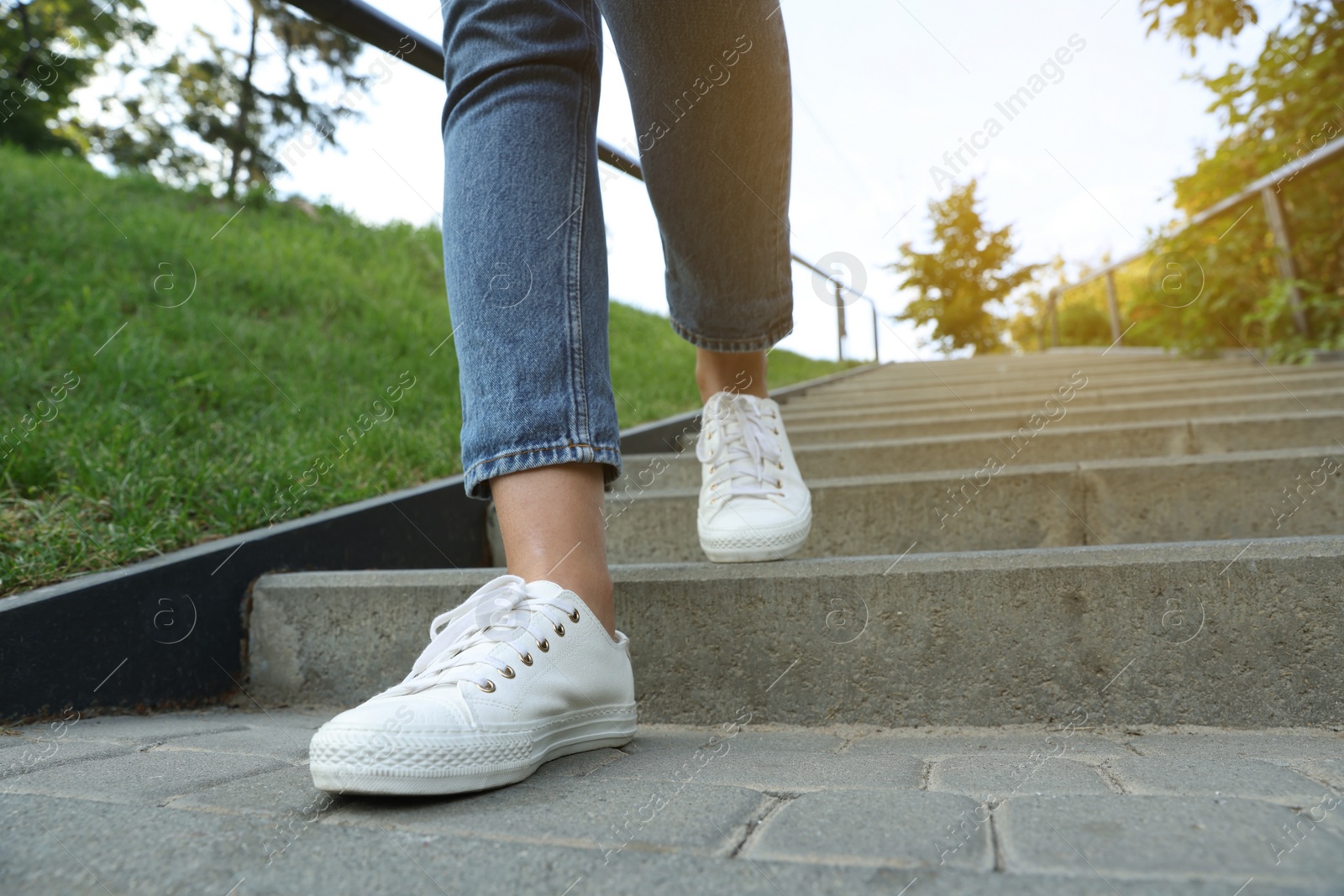 Photo of Woman in stylish black sneakers walking down stairs, closeup