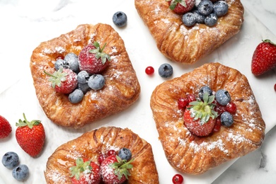 Photo of Fresh delicious puff pastry with sweet berries on white marble board, top view