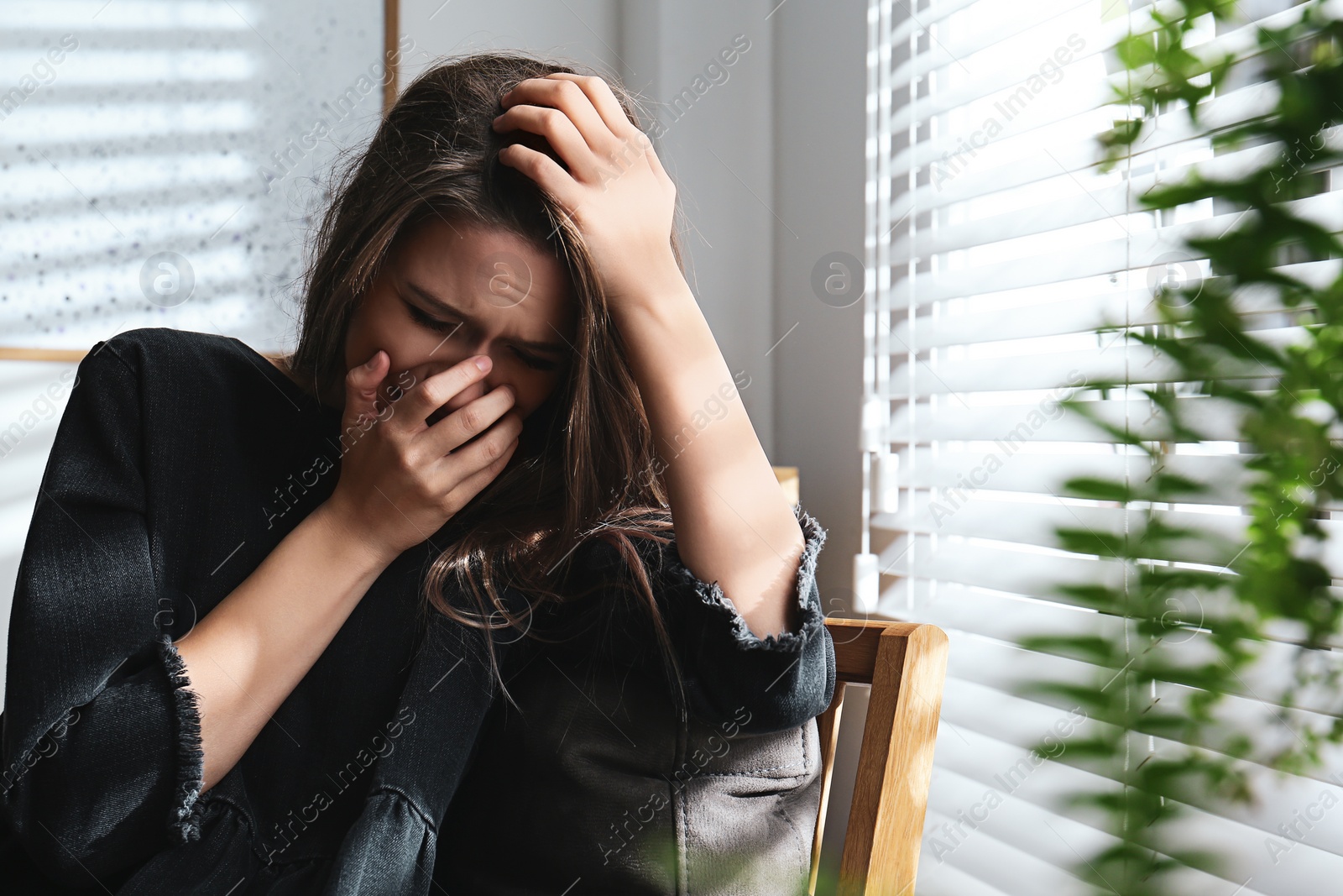 Photo of Abused young woman crying indoors. Domestic violence concept