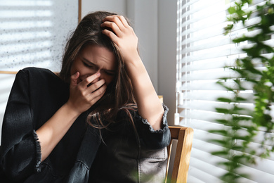 Abused young woman crying indoors. Domestic violence concept