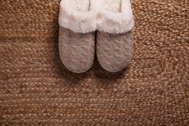 Photo of Pair of warm stylish slippers on wicker carpet, top view. Space for text