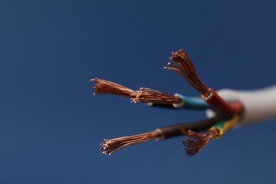 Photo of Cable with stripped wires on blue background, closeup