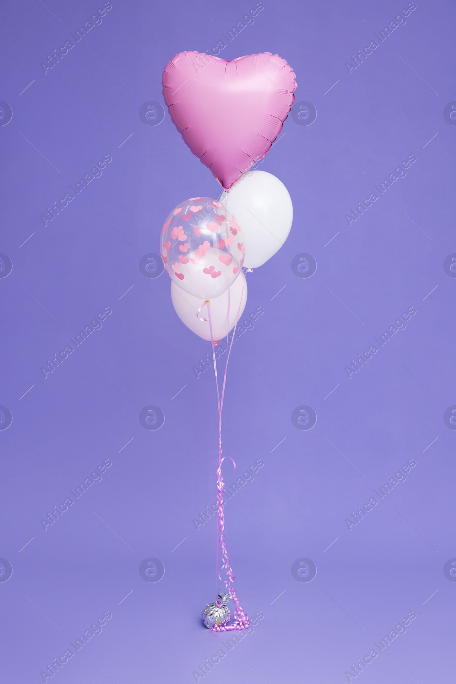 Photo of Bunch of heart and round shaped balloons for birthday party on violet background