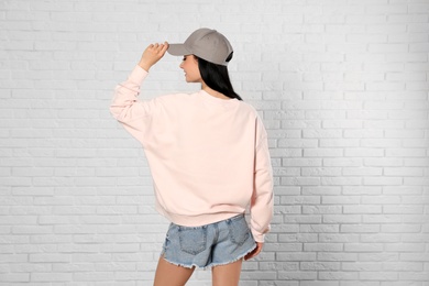 Young woman in sweater at brick wall. Mock up for design