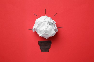 Idea concept. Light bulb made with crumpled paper and drawing on red background, top view