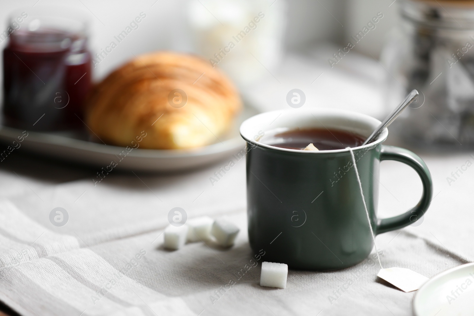 Photo of Cup of freshly brewed tea and sugar cubes on table