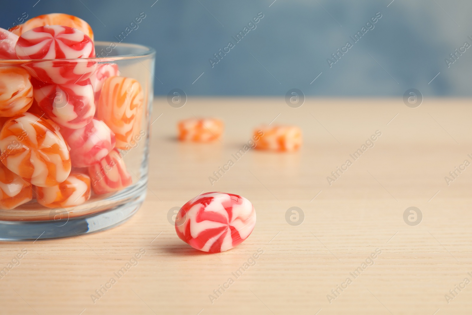 Photo of Glass with delicious colorful candies on wooden table. Space for text