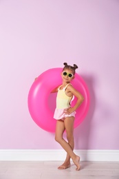 Photo of Cute little girl with inflatable ring near color wall