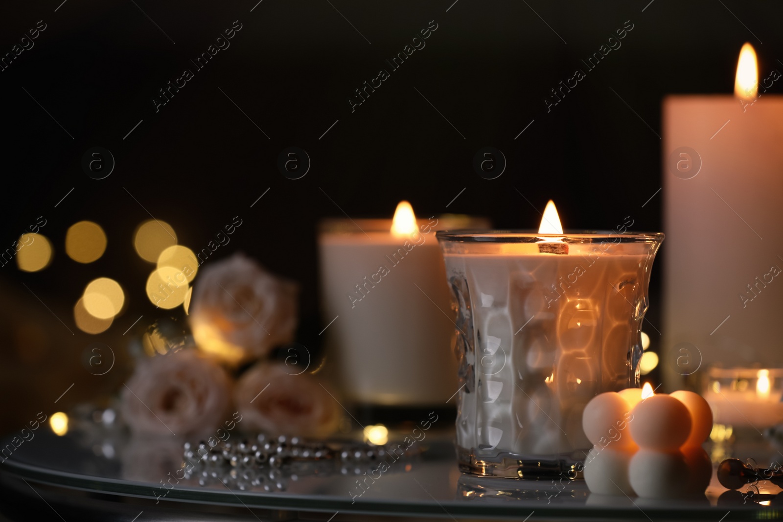 Photo of Beautiful burning candles on table in darkness. Space for text