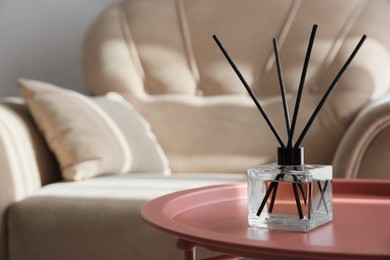 Photo of Aromatic reed air freshener on table indoors, space for text