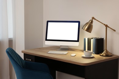 Image of Comfortable workplace at home. Modern computer with blank screen and lamp on wooden desk. Mockup for design