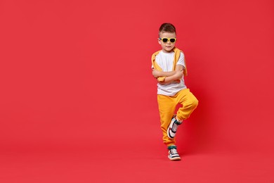 Photo of Happy little boy dancing on red background. Space for text