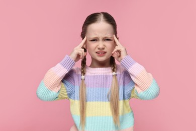 Little girl suffering from headache on pink background