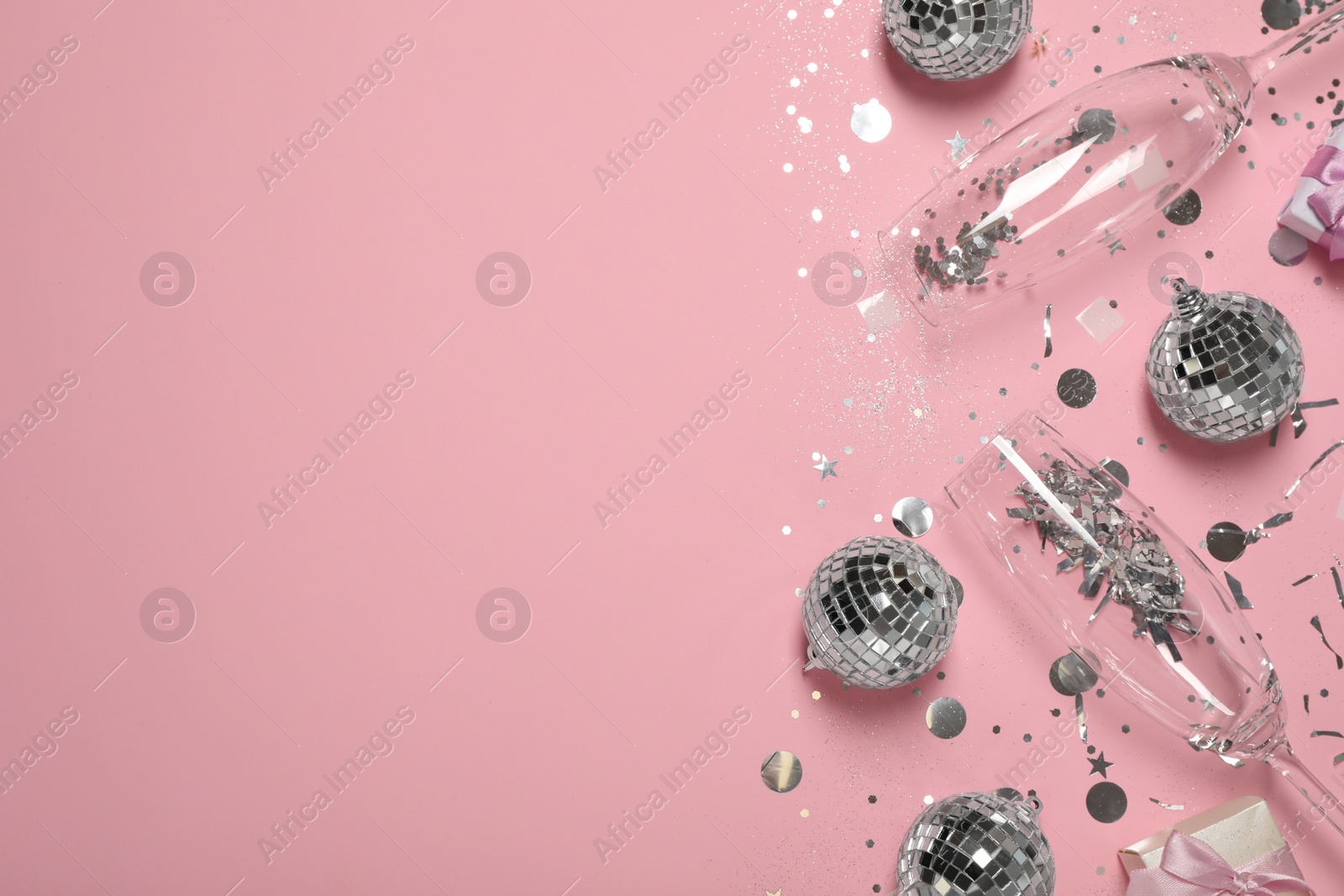 Photo of Bright shiny disco balls, confetti and glasses on pink background, flat lay. Space for text