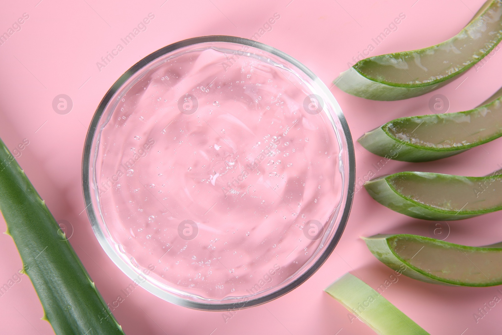 Photo of Aloe vera leaves and cosmetic gel on pink background, top view