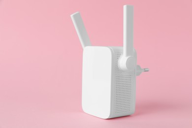 Photo of New modern Wi-Fi repeater on pink background, space for text