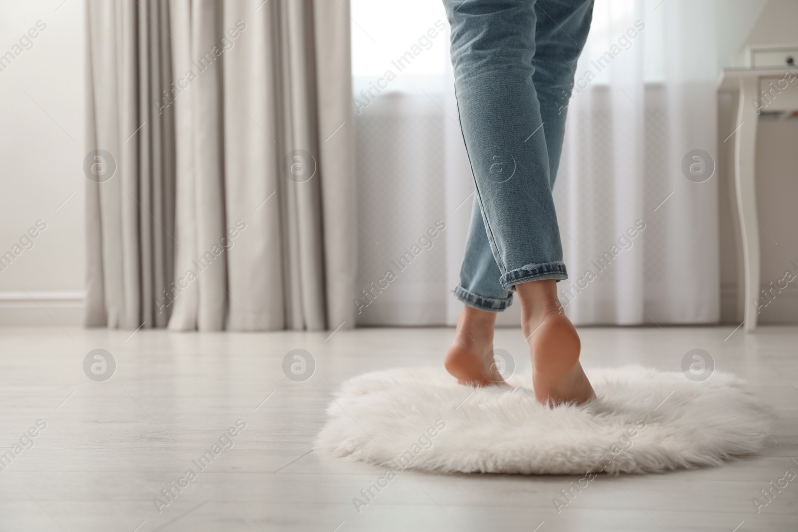 Photo of Woman standing on faux fur rug at home, closeup. Space for text