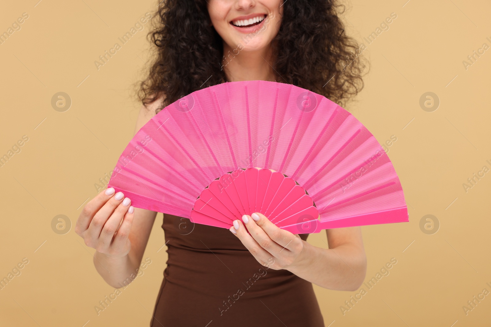 Photo of Woman holding hand fan on beige background, closeup