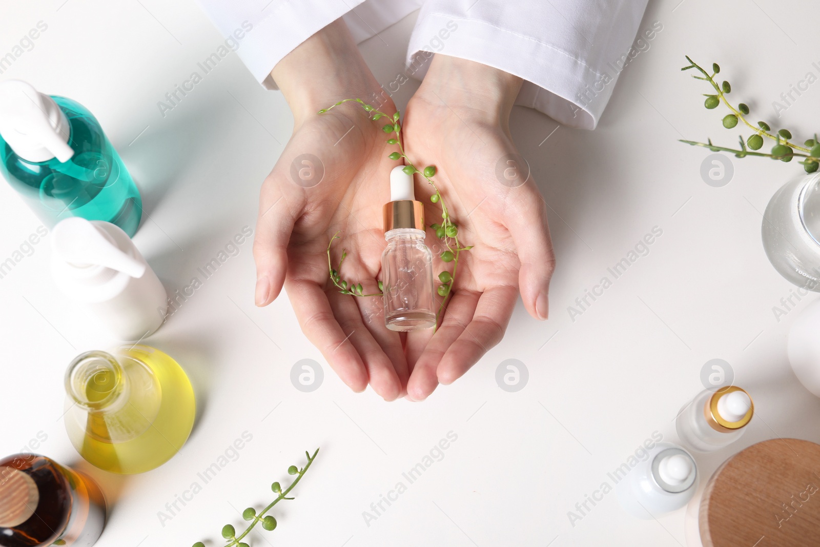 Photo of Dermatologist with bottle of essential oil at white table, top view. Development and testing