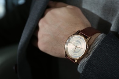 Photo of Man wearing luxury wrist watch with leather band, closeup