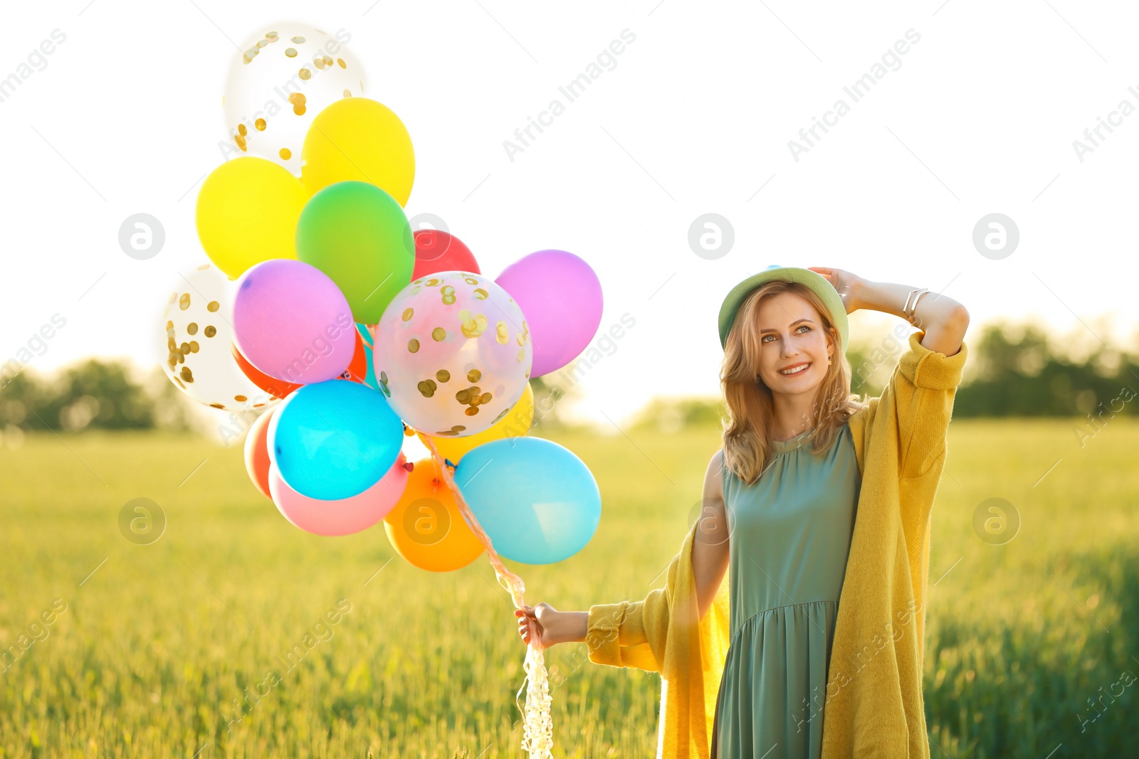 Photo of Young woman with colorful balloons in field on sunny day