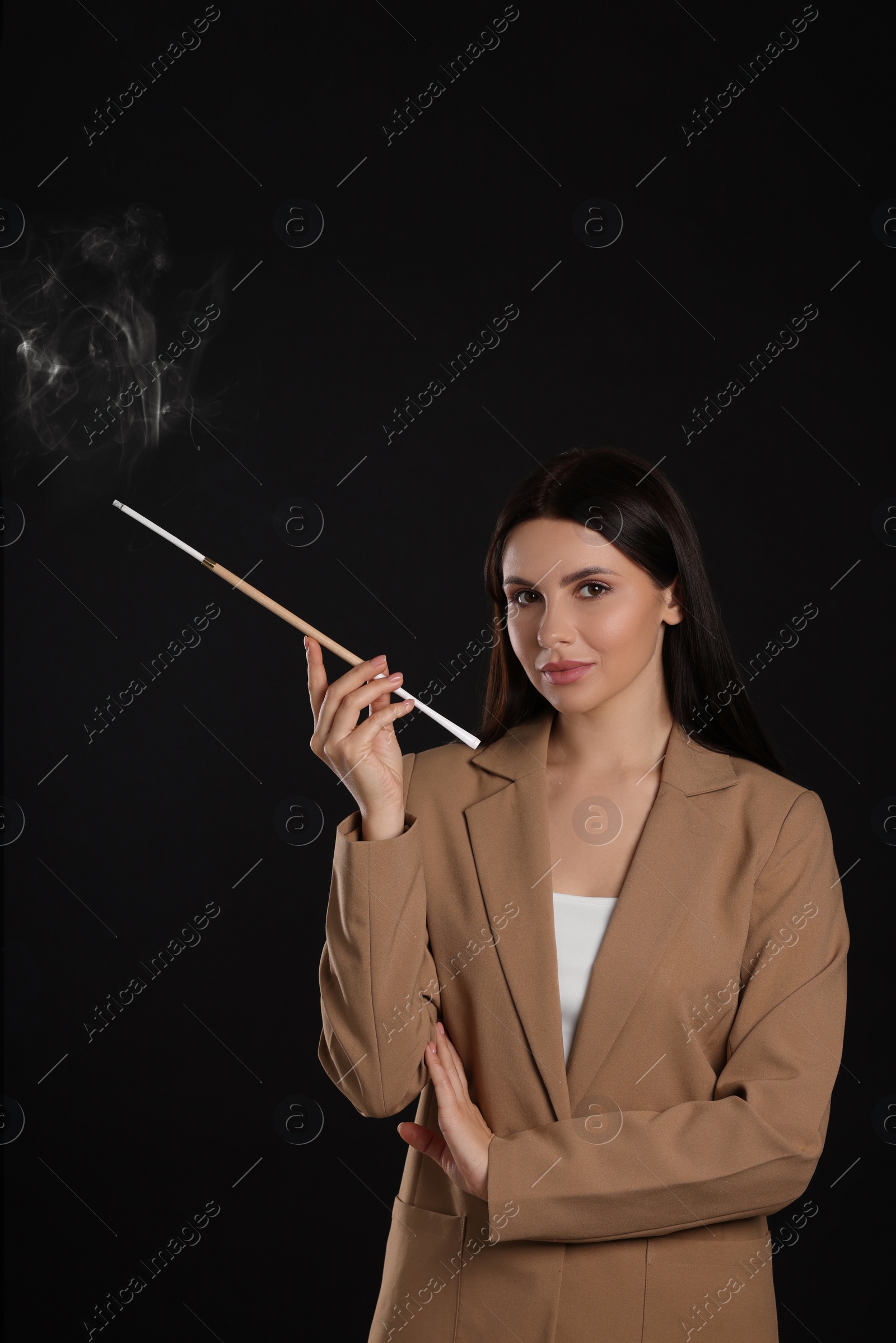 Photo of Woman using long cigarette holder for smoking on black background, space for text