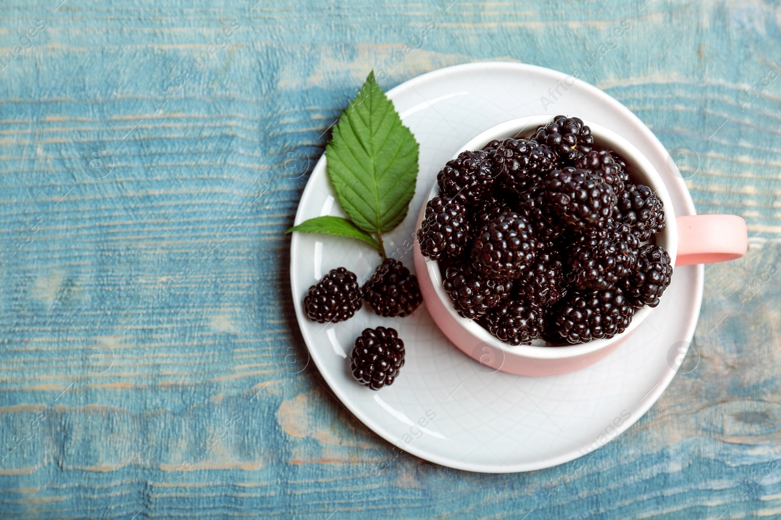 Photo of Mug of fresh blackberry on wooden background, top view