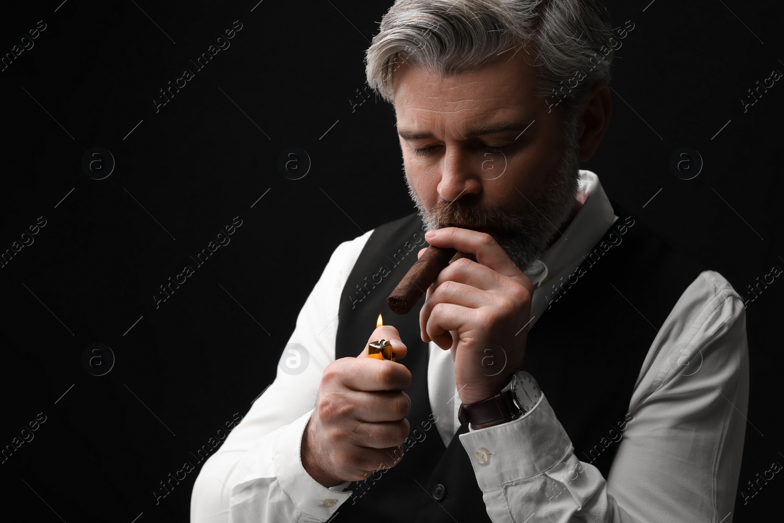 Photo of Bearded man lighting cigar on black background. Space for text