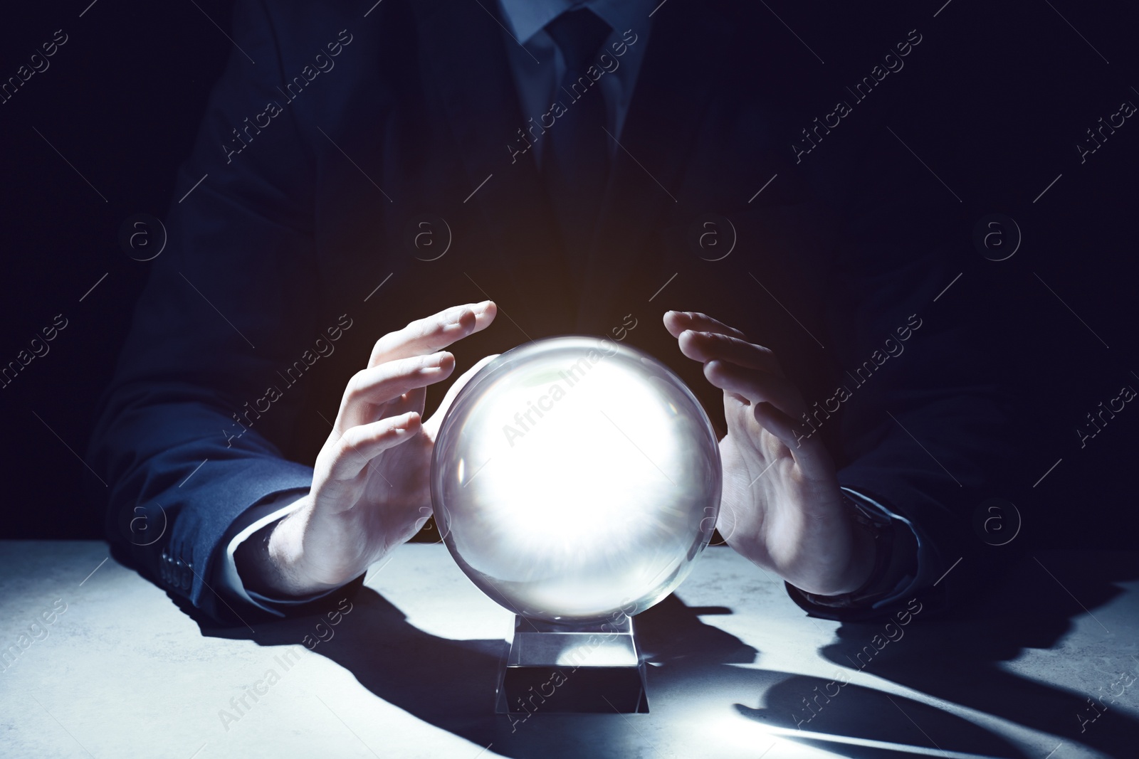 Photo of Businessman using crystal ball to predict future at table in darkness, closeup