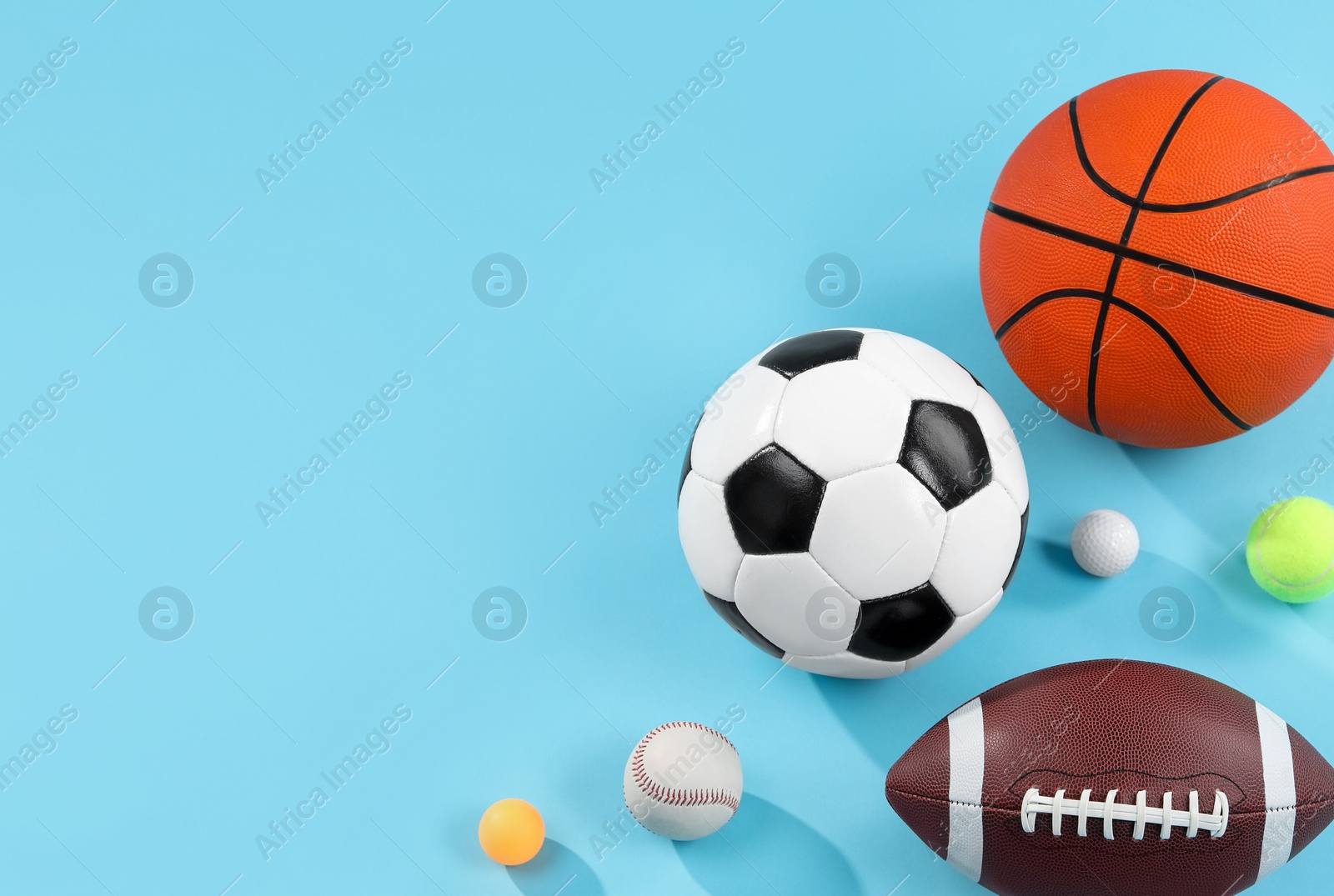 Photo of Many different sports balls on light blue background, flat lay. Space for text