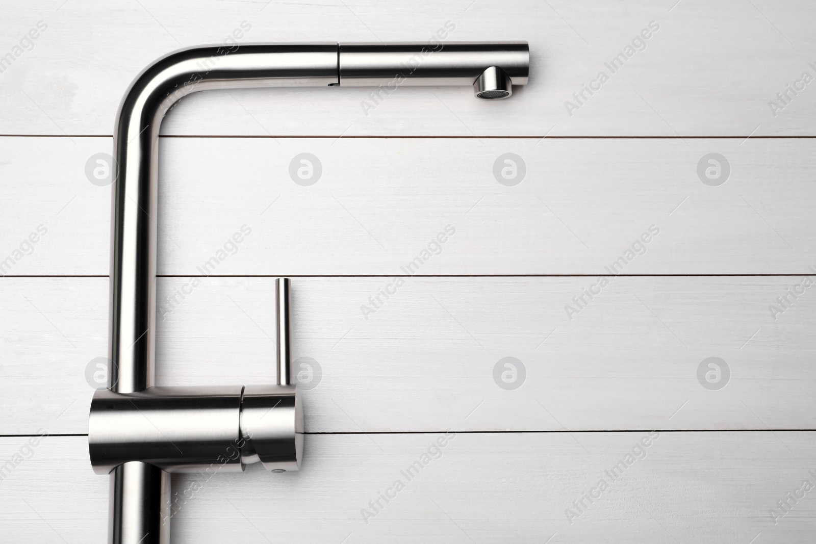 Photo of Modern pull out kitchen tap on white wooden table, top view. Space for text