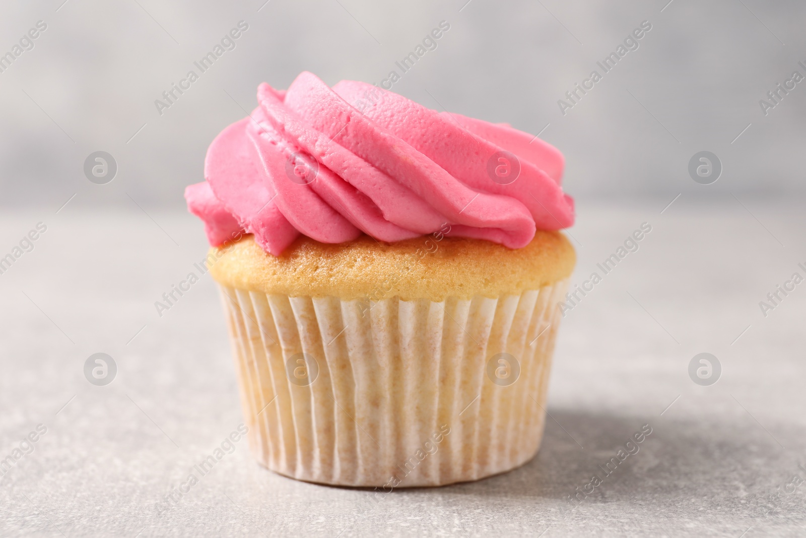 Photo of Delicious cupcake with bright cream on gray table