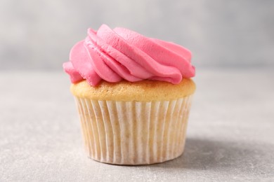 Photo of Delicious cupcake with bright cream on gray table