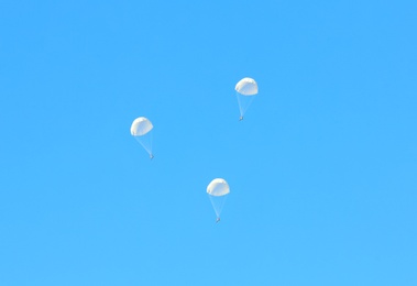 Photo of Paratrooper parachuting in blue sky. Military service