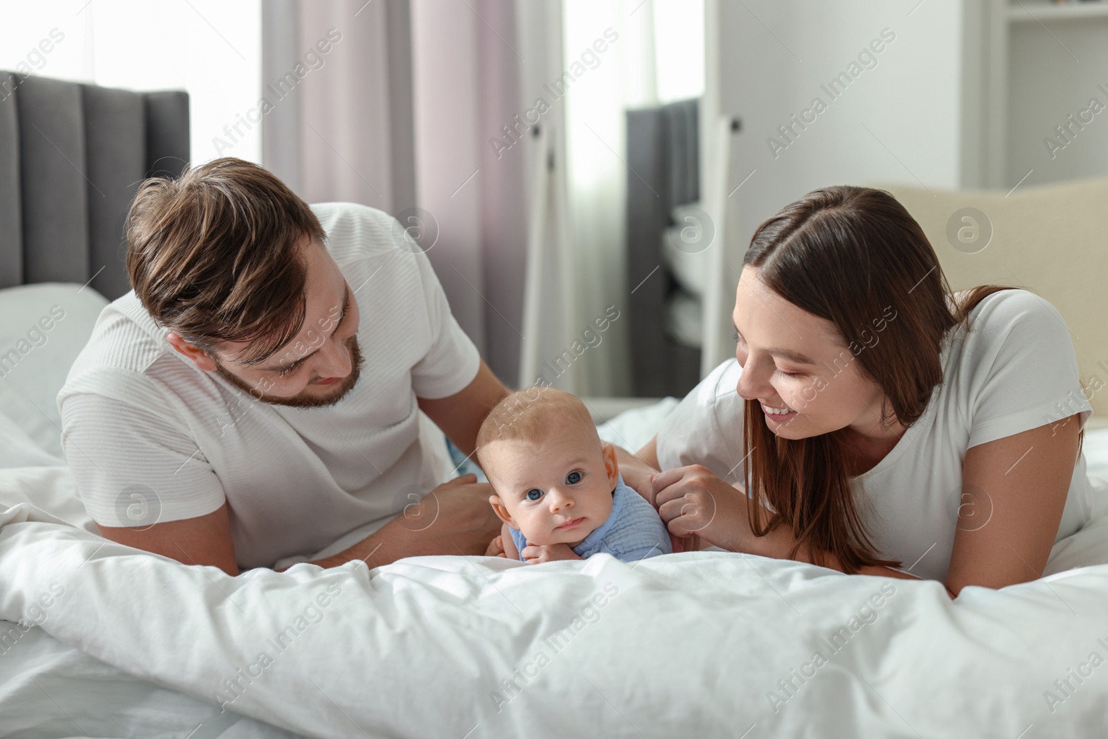 Photo of Happy family. Parents with their cute baby on bed indoors