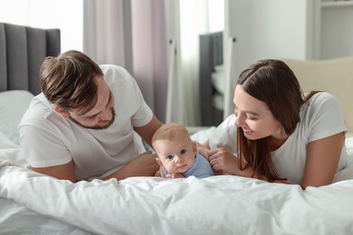 Happy family. Parents with their cute baby on bed indoors