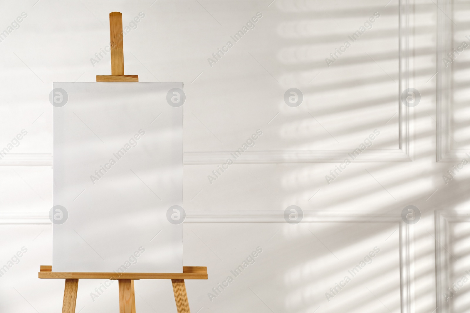 Photo of Wooden easel with blank canvas on light background. Space for text